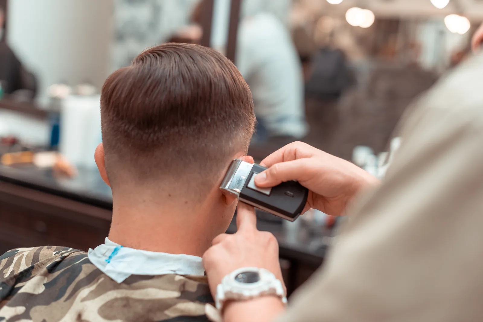 Fryzjer strzyże włosy klienta maszynką w salonie